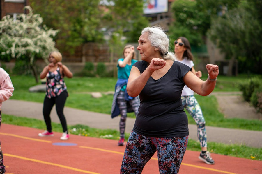 Mujer adulta mayor haciendo ejercicio al aire libre con un grupo