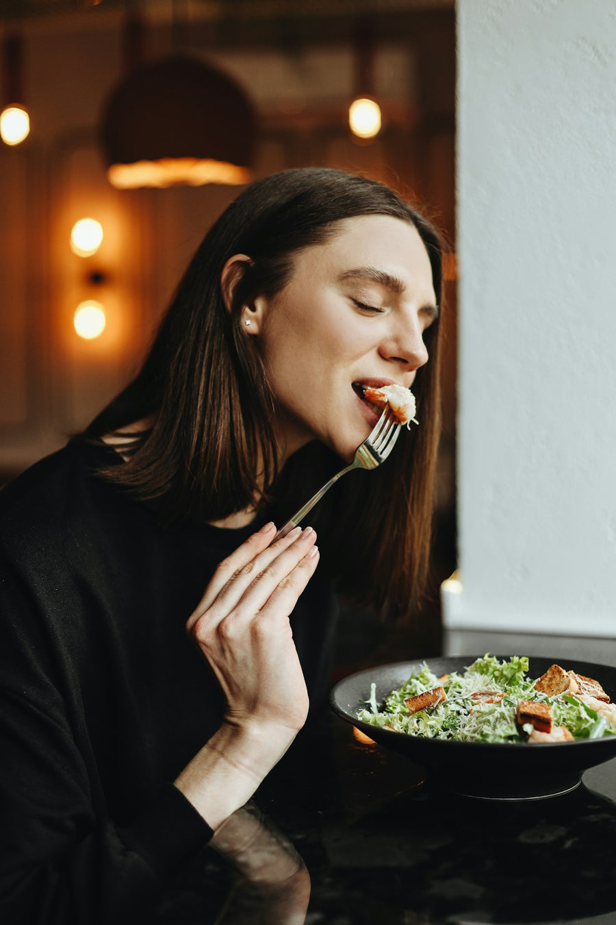 Mujer comiendo una ensalada con tenedor