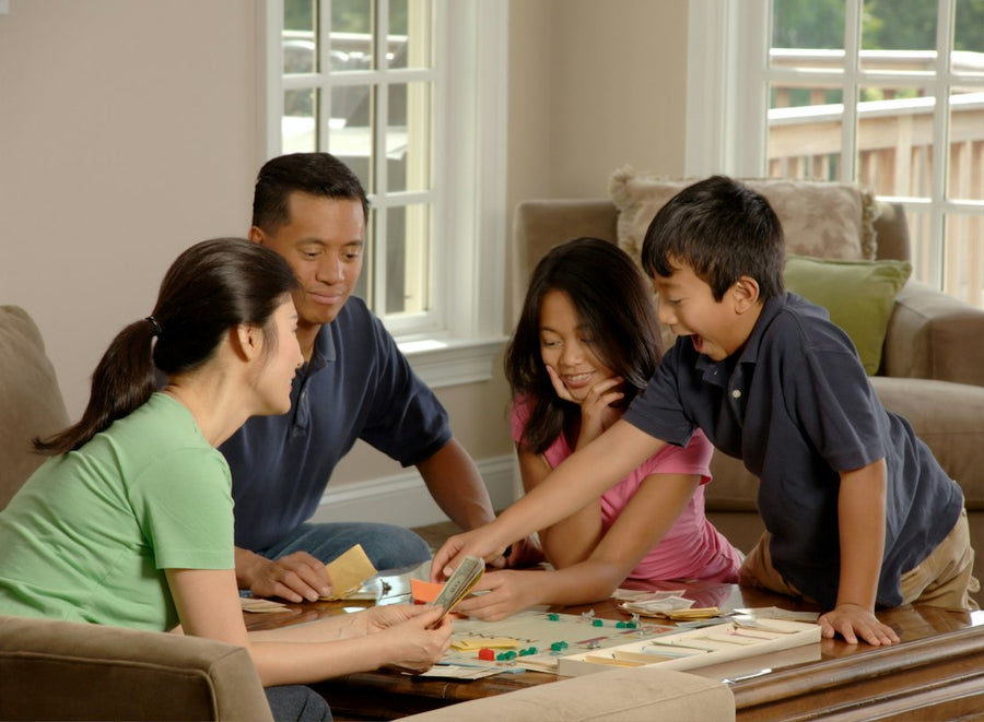 Mamá, papá y sus dos hijos juegan un juego de mesa en la sala