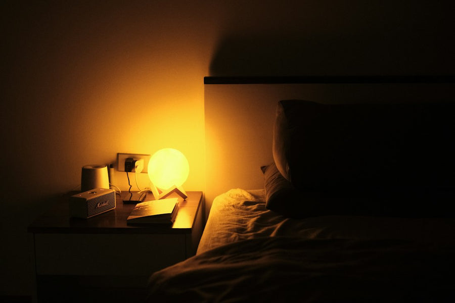 Buró con una lámpara de luna de luz cálida junto a la cama, de noche