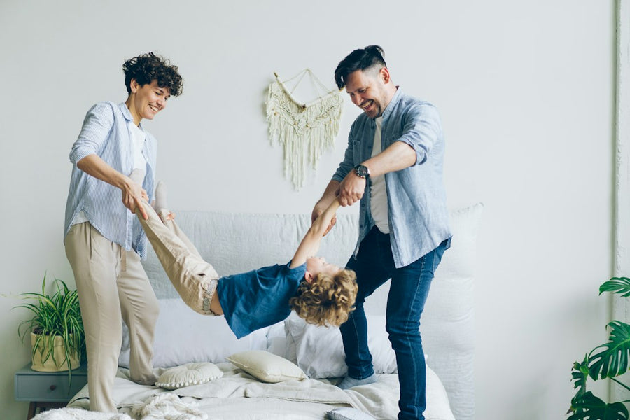 Mamá y papá juegan con su hijo sobre la cama
