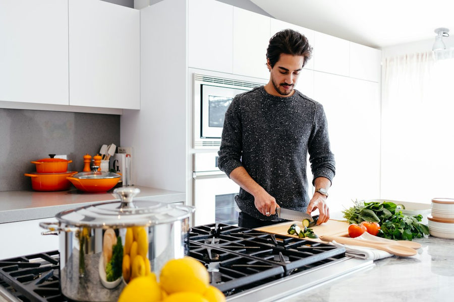 Hombre cortando verduras en la barra de su cocina