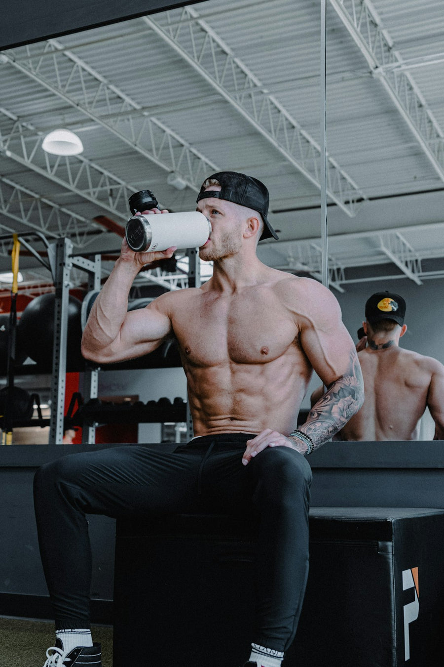 Hombre en el gimnasio tomando de su botella entre una serie y otra