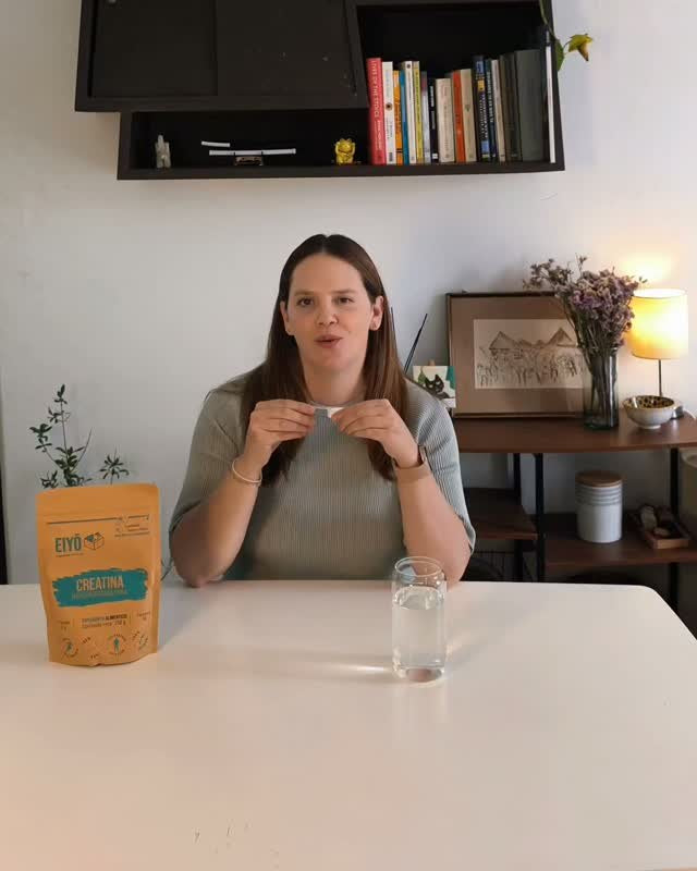 Marielle en la mesa con la bolsa de creatina EIYŌ y un vaso de agua