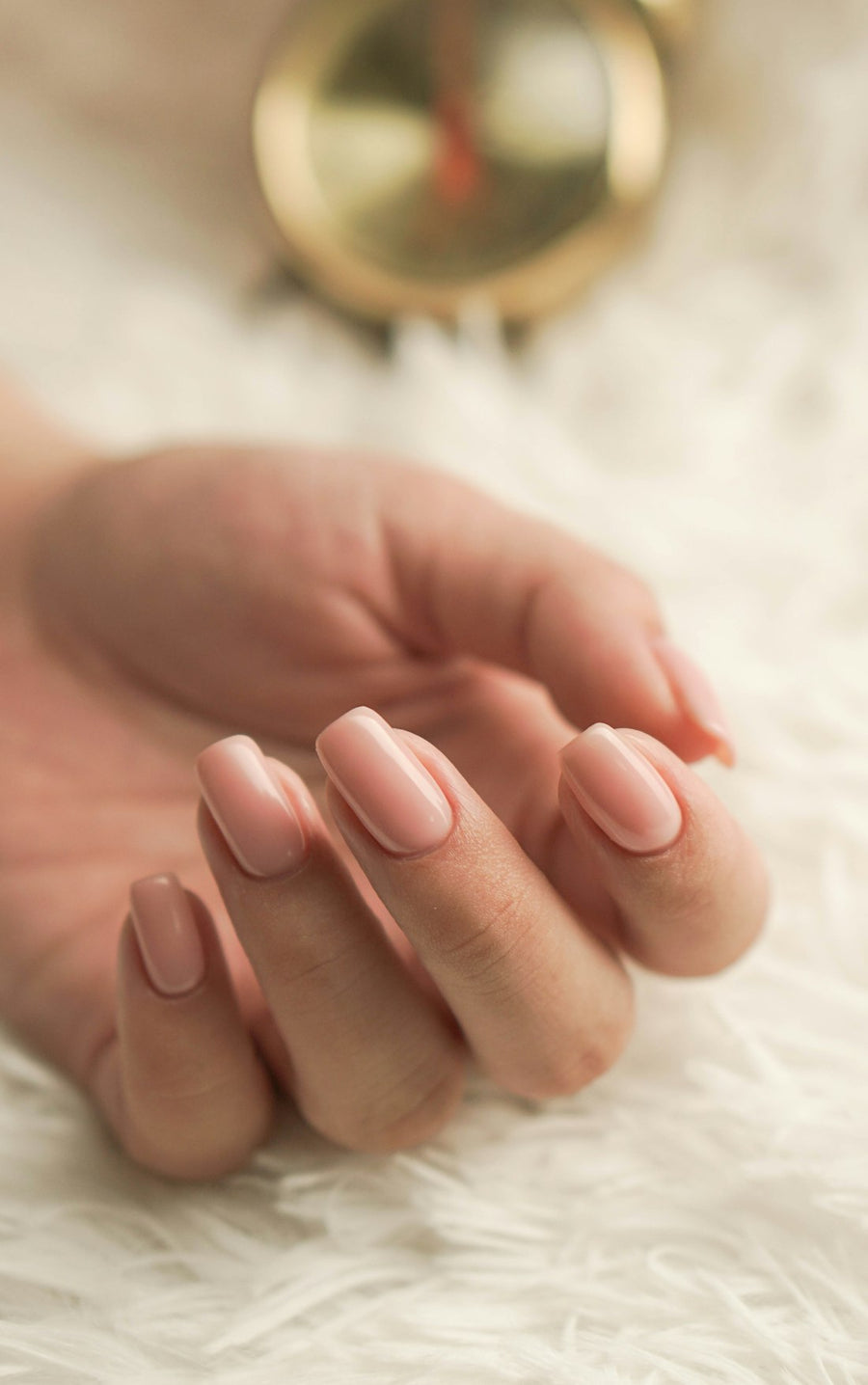 Mano de mujer con uñas naturales cuidadas, en tono rosa claro