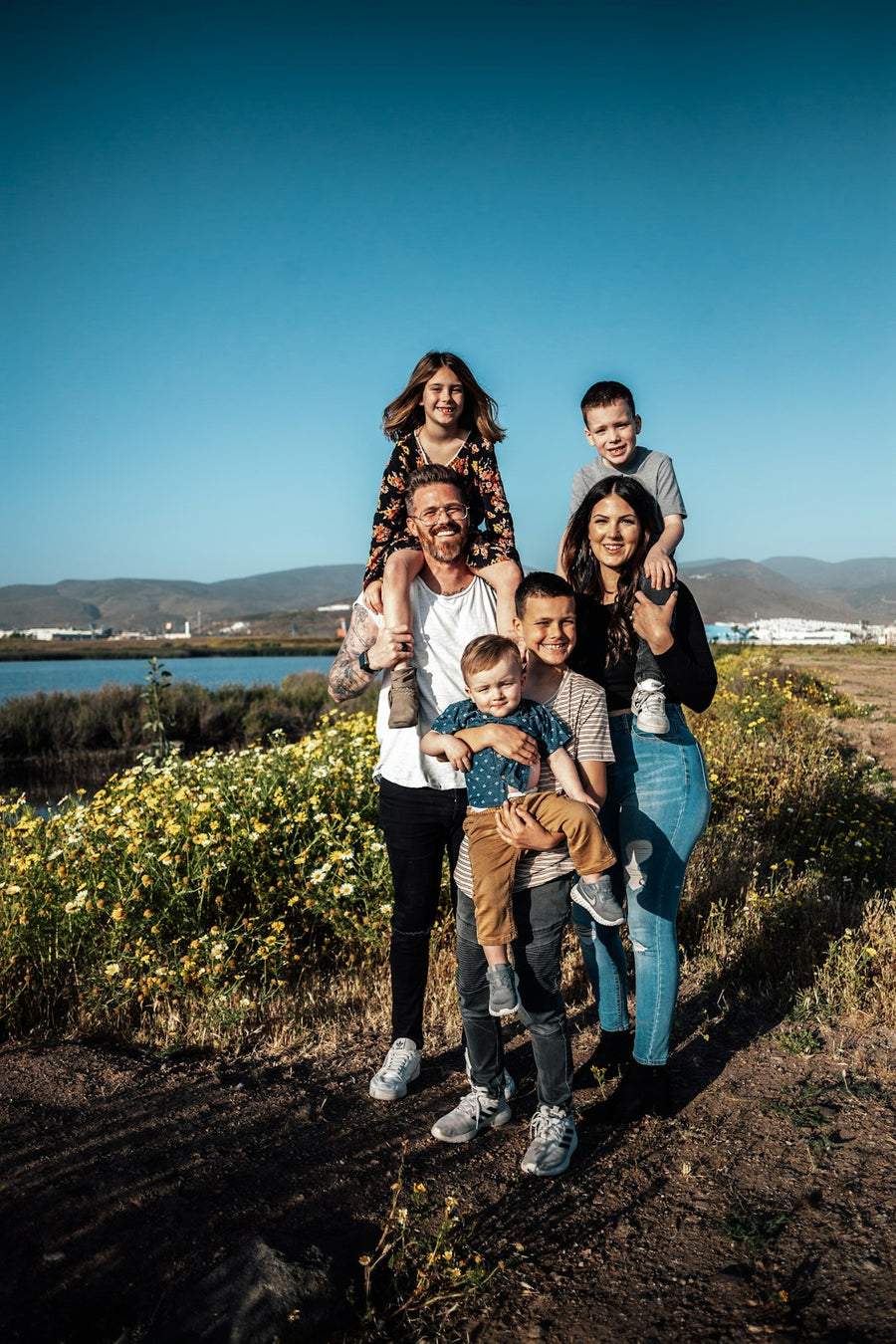 Papá y mamá con sus cuatro hijos al aire libre, con los niños en brazos y en hombros