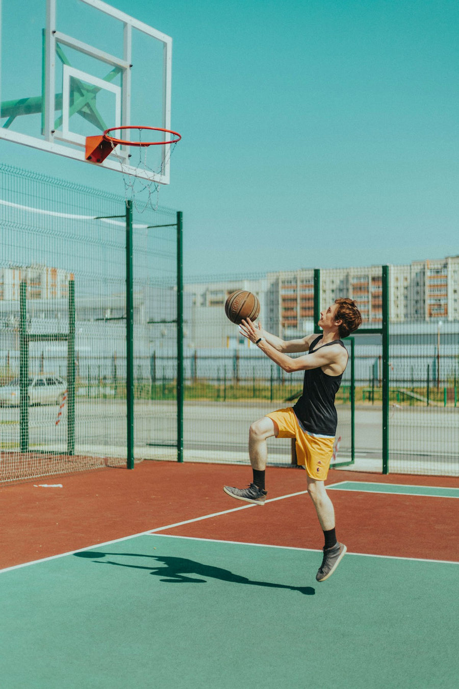 Joven lanzando a la canasta en una cancha al aire libre