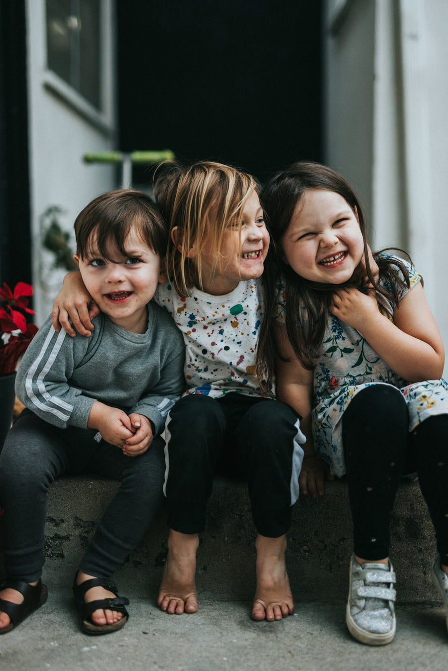 Tres niños sonríen sentados juntos
