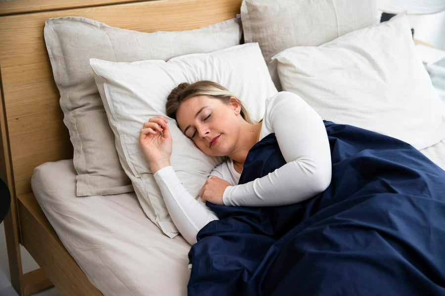 Mujer durmiendo tranquila en su cama con una cobija azul marino